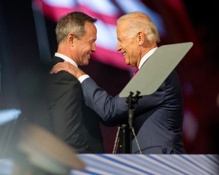 two men in suits on stage touching hands