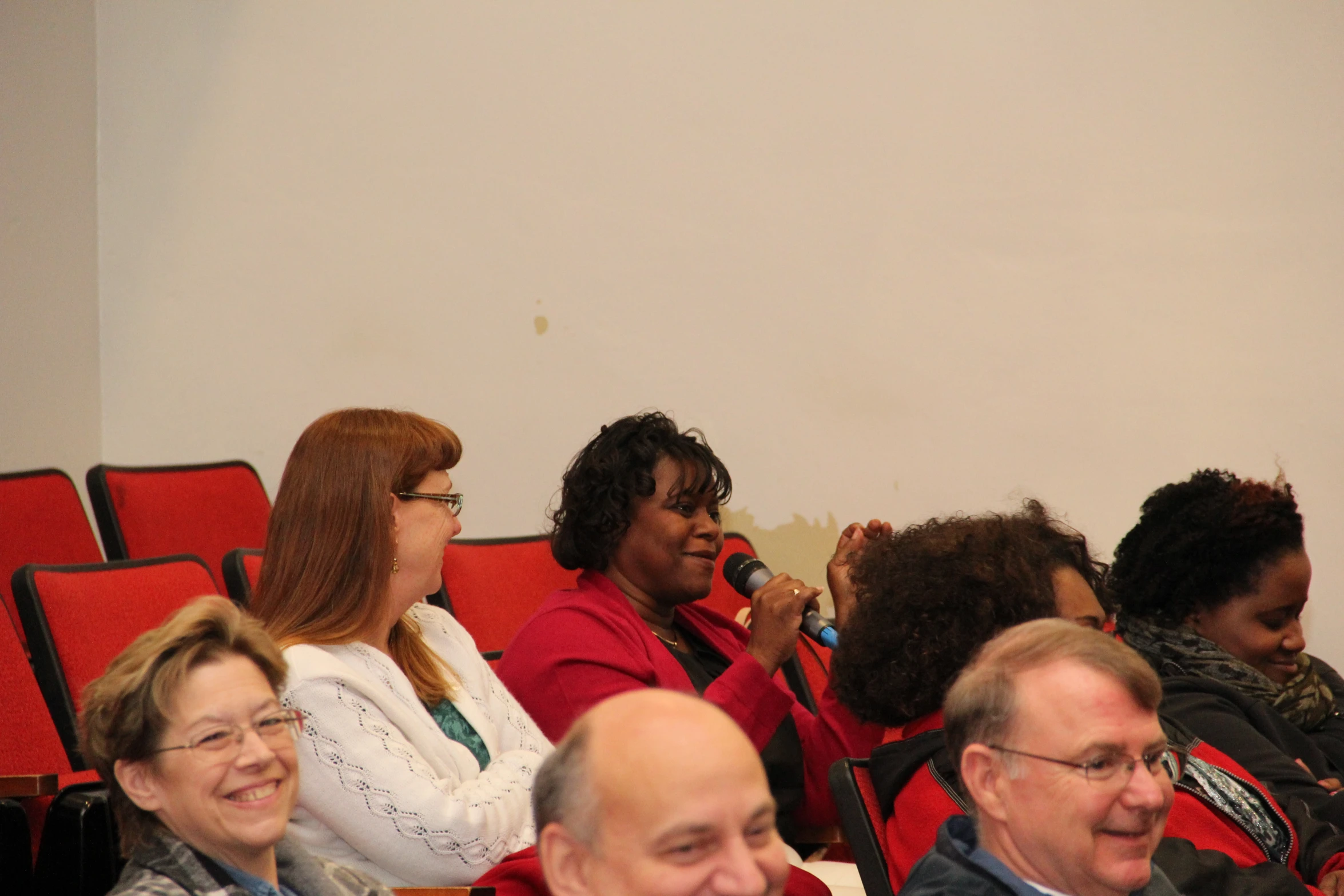 people sitting together in red seats in a room