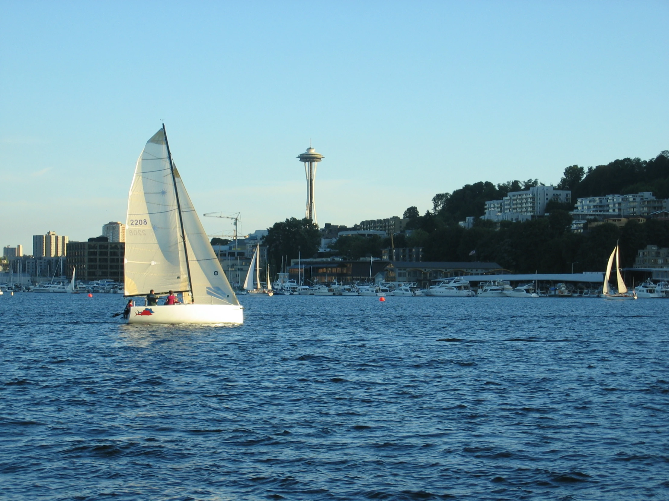 sailboat in the middle of the ocean with city behind