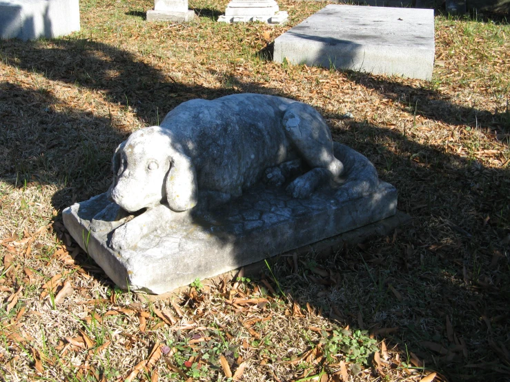 a stone statue sitting in the grass next to headstones