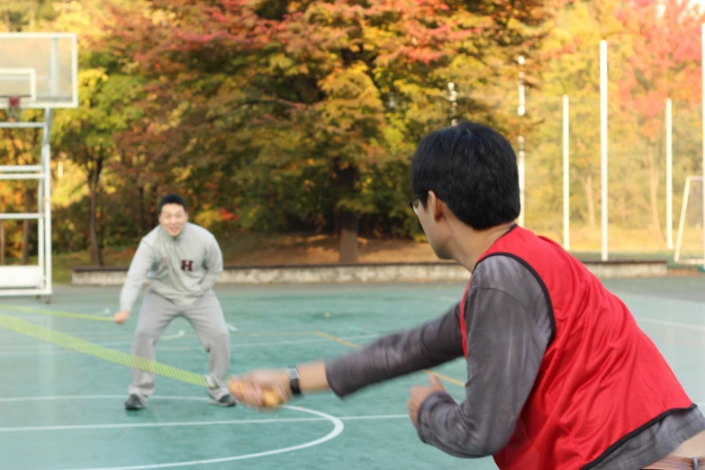 two young men are playing basketball outside together