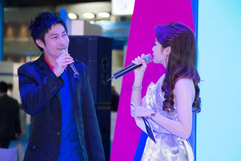 two people are holding microphones and singing in front of a screen