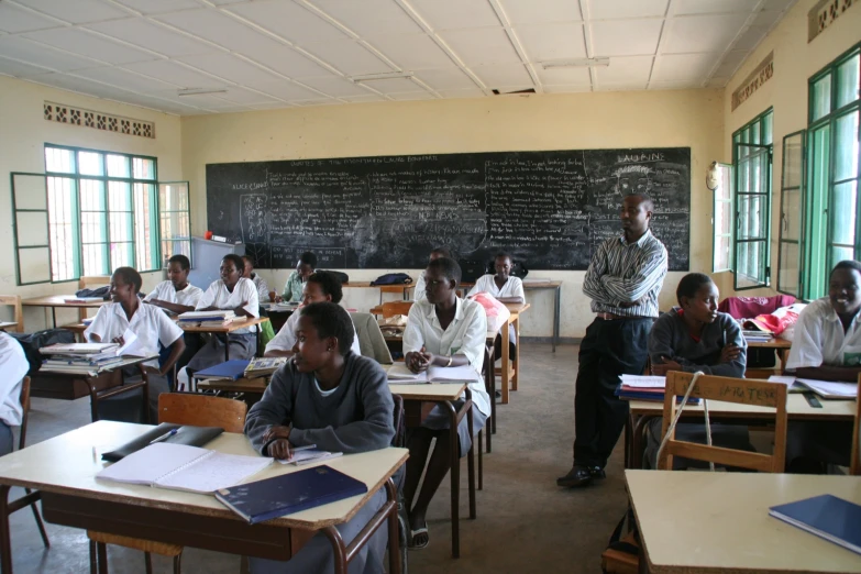 school s taking class in a classroom with blackboard