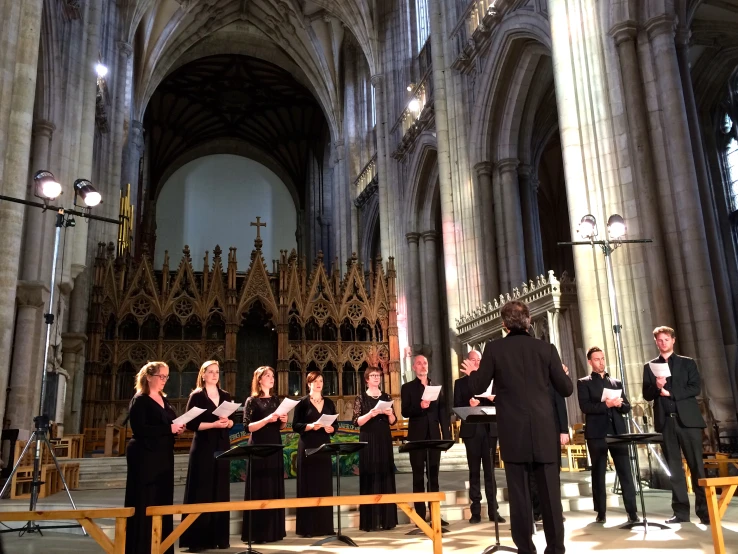 choirs standing in a church with the conductor and two male choirists