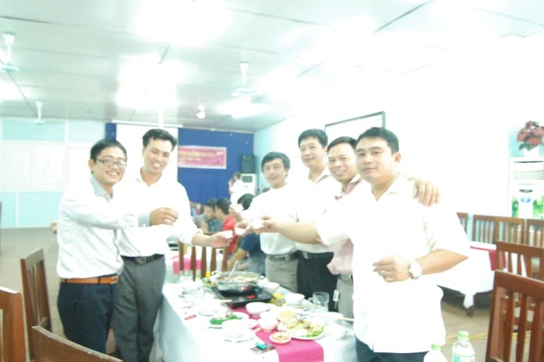 several men are gathered in a restaurant to put food on a table