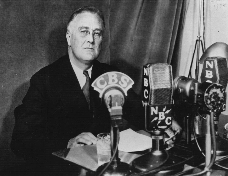 a man sits at a desk in front of old microphones