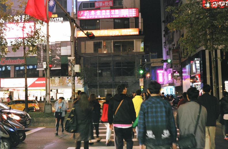 people crossing the street at night in a city