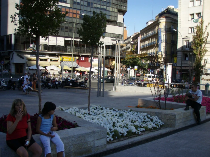 two girls sitting on the ledge with some flowers