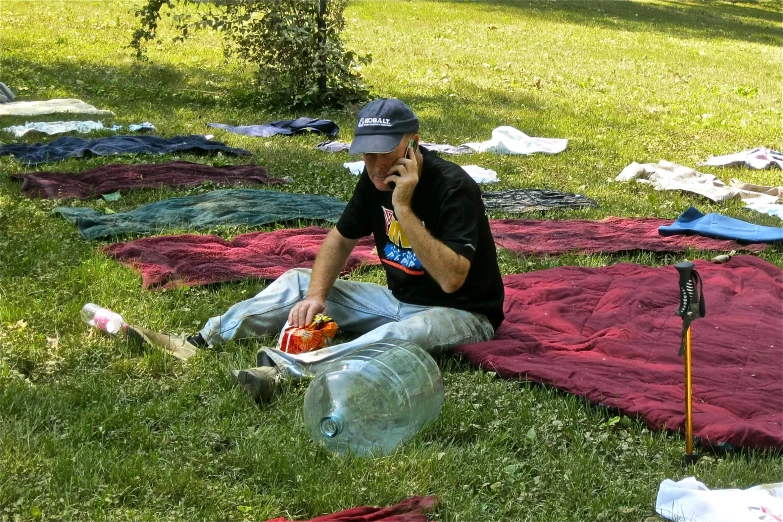 a man sitting on the ground while talking on a cell phone