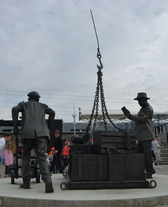 a statue with men attached to it and some people on the ground