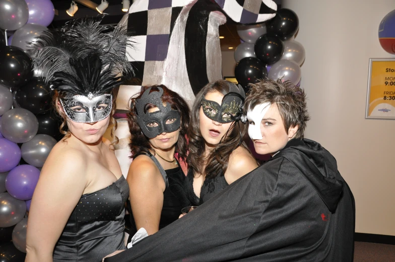 three women are posing with a man in mask