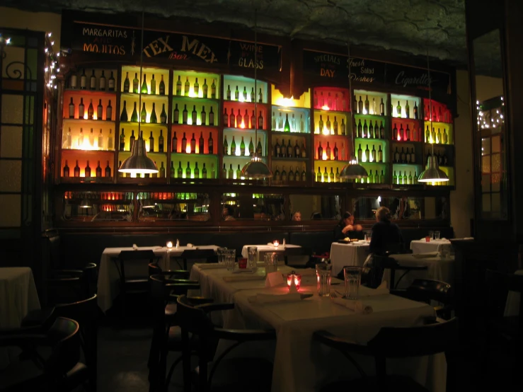 a dimly lit restaurant dining area with candle lights and colorful display