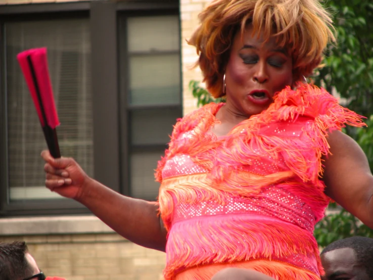 a woman wearing an orange and pink outfit holding a red bat