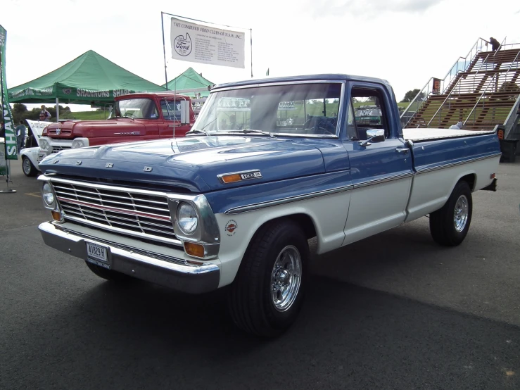 the blue and white truck is parked in front of other trucks