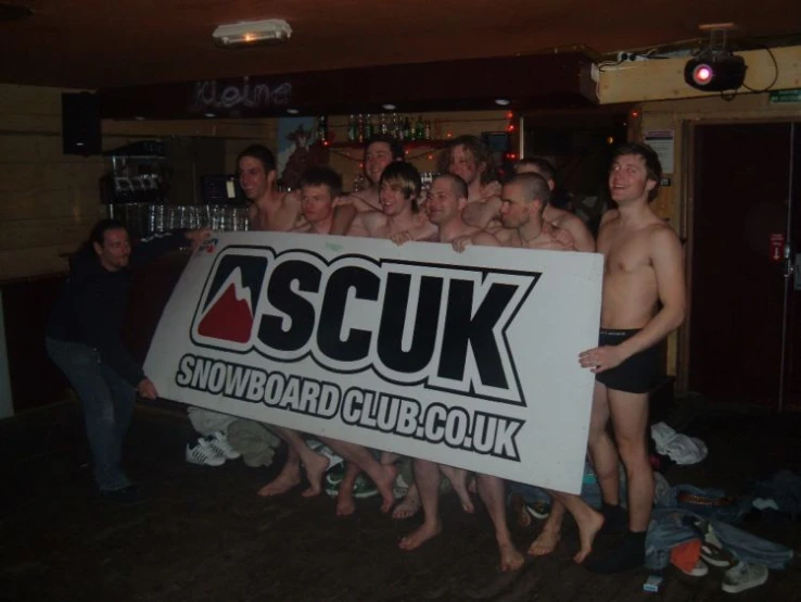 several men are standing in a bar and holding a sign