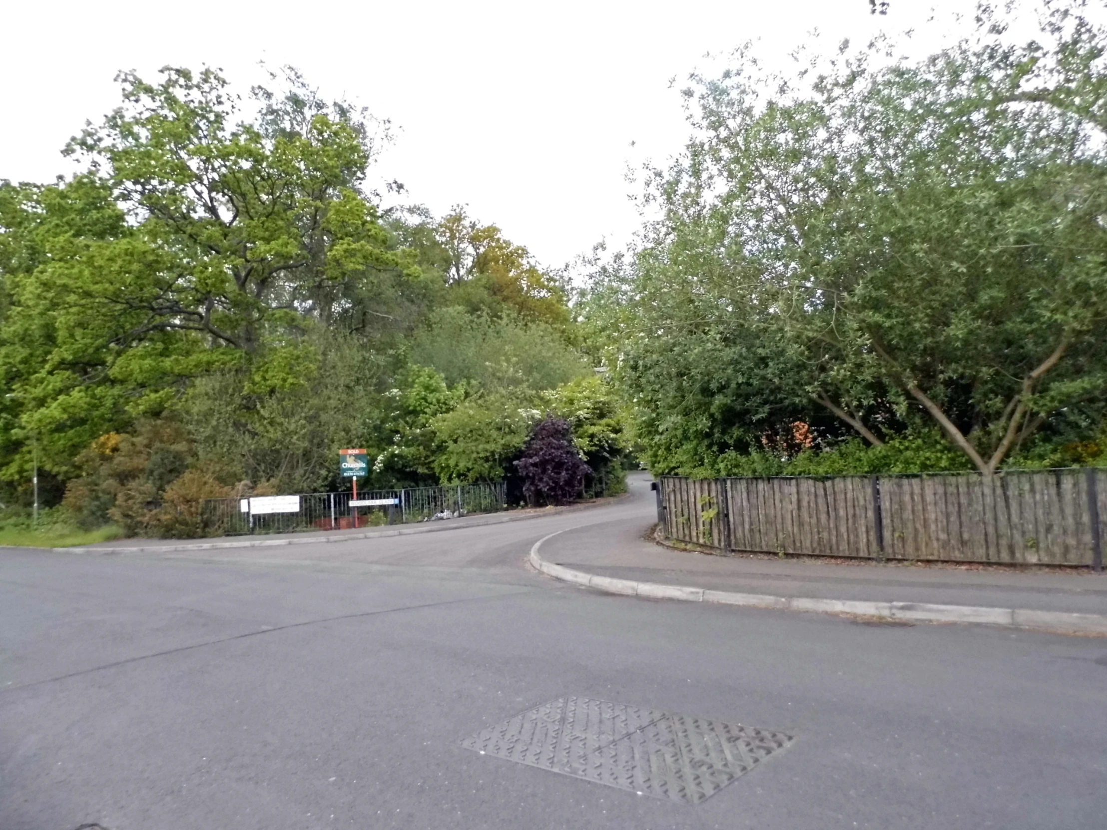 the street has an empty curved road next to a fence