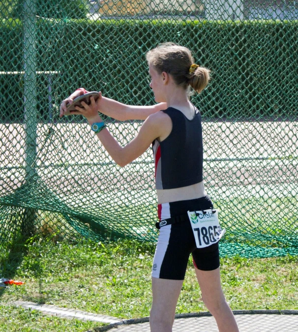 young woman throwing softball on batting mound in park