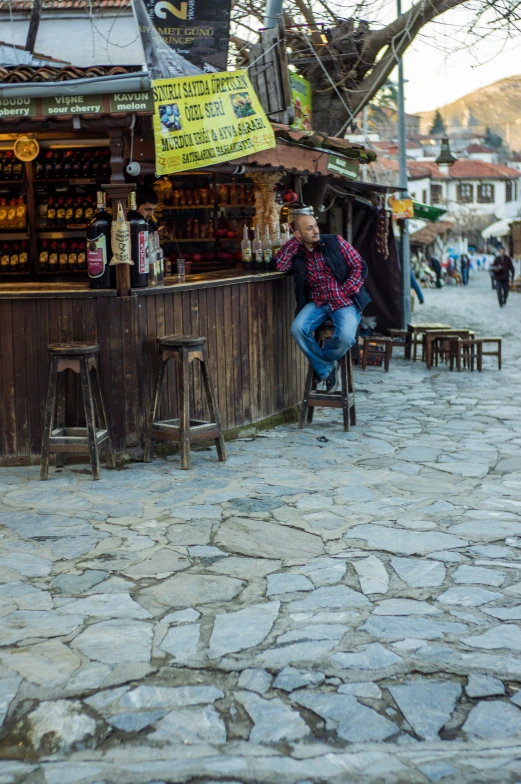 man leaning on a stool at the street market