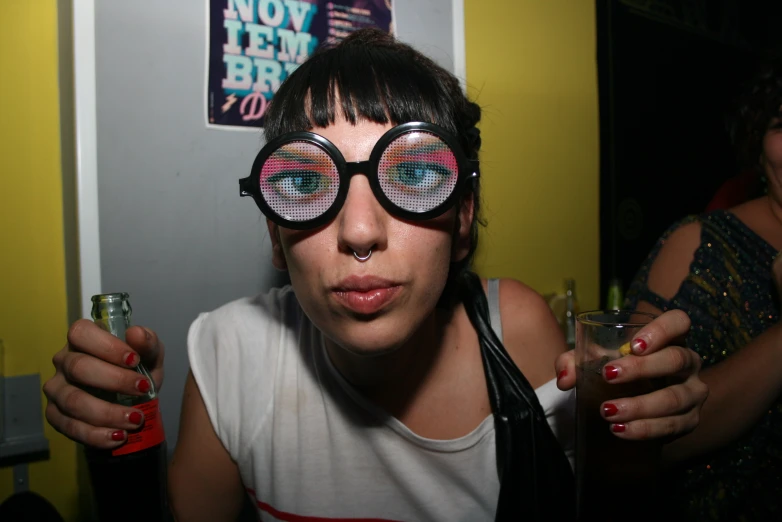 a woman wearing large round sunglasses and drinking