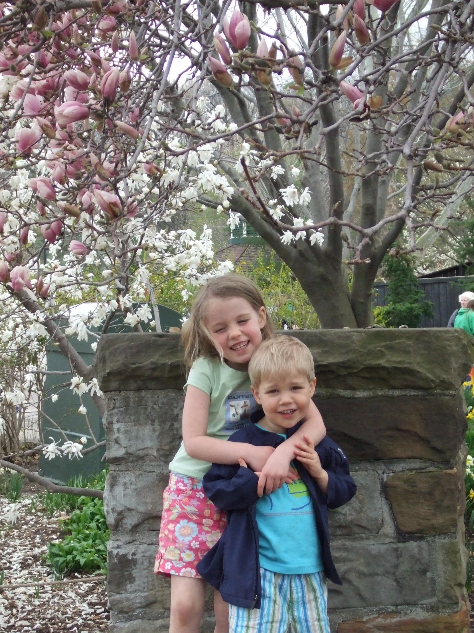 two young children hugging each other in front of a tree