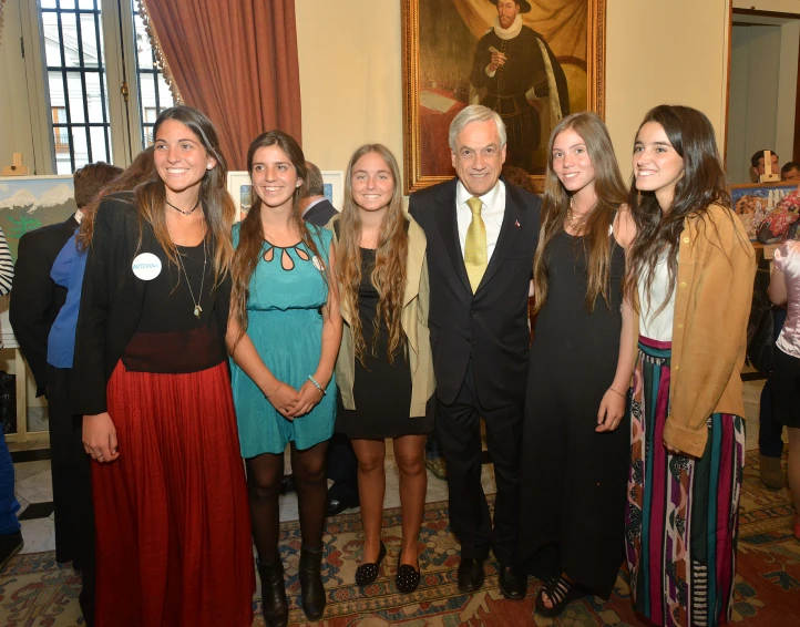 a group of people standing together next to a painting