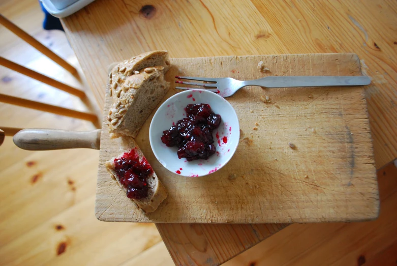 a piece of bread with fruit jam on it on a  board