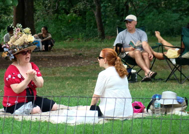 a woman sitting on the grass talking to another lady with flower crowns