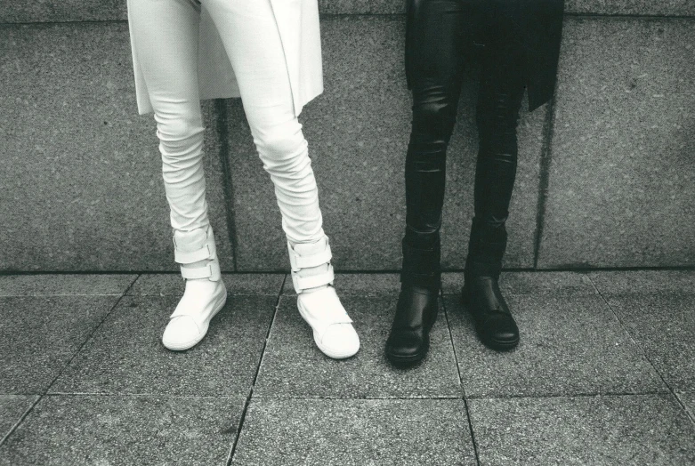 two people standing next to each other on a sidewalk