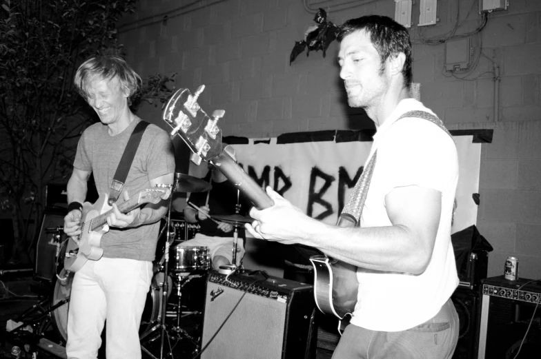 two young men playing music with guitar strings