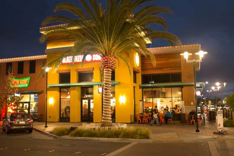 the street with people in front of the restaurant at night