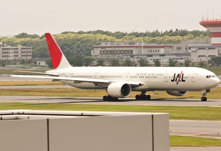 large white airliner with red trim parked on a runway