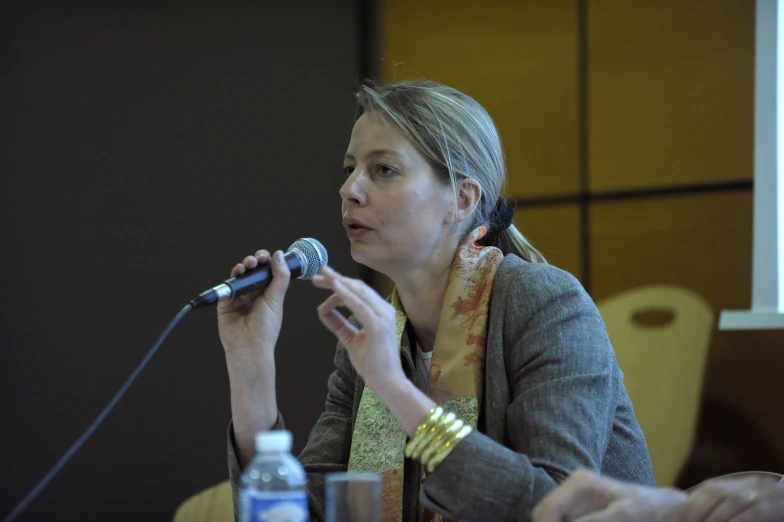 a woman speaking into a microphone next to another woman