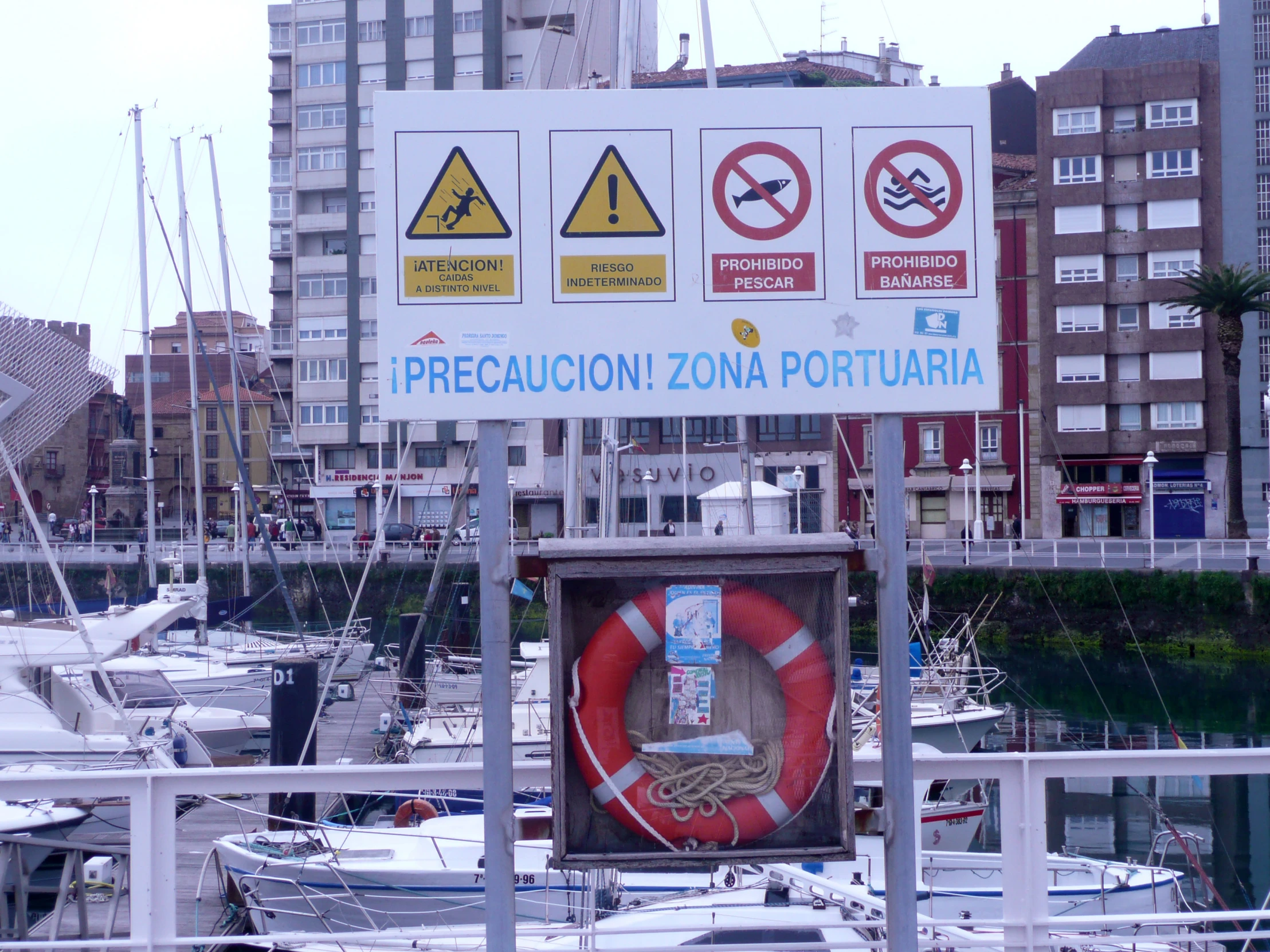 a large sign posted near the water near some boats