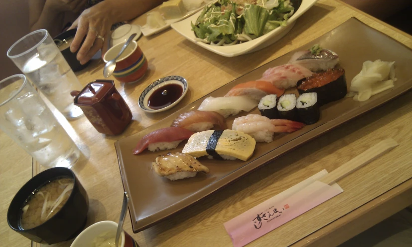 a wooden table topped with plates of sushi