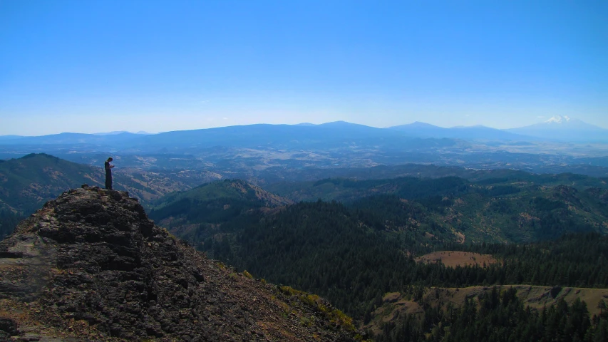 a person stands on top of a large rock