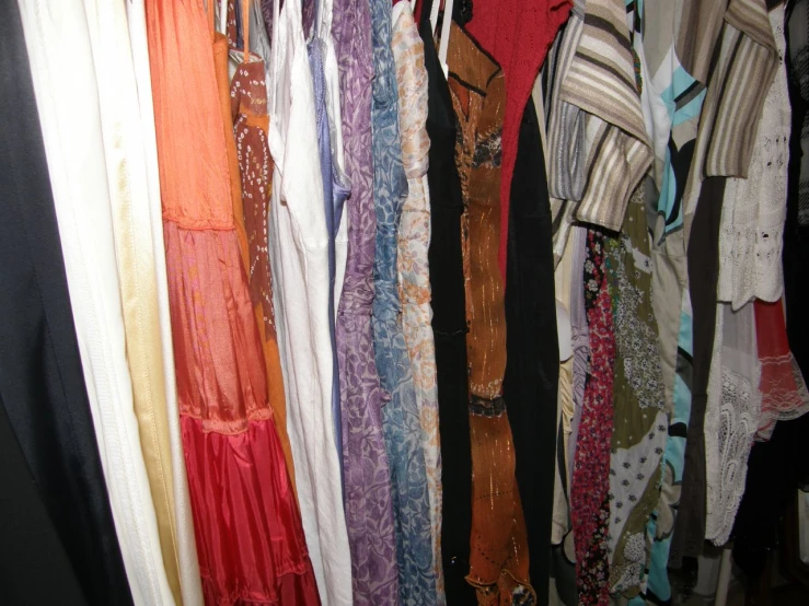 several rows of long dress shirts hanging on racks