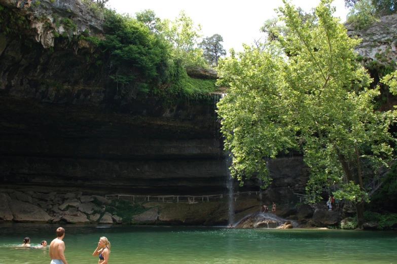 three people are standing on the bank and some water