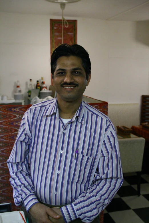 the man smiles in his striped shirt while posing