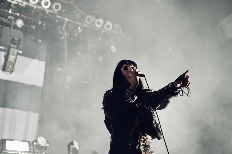 a young lady with dark makeup holding a microphone on stage