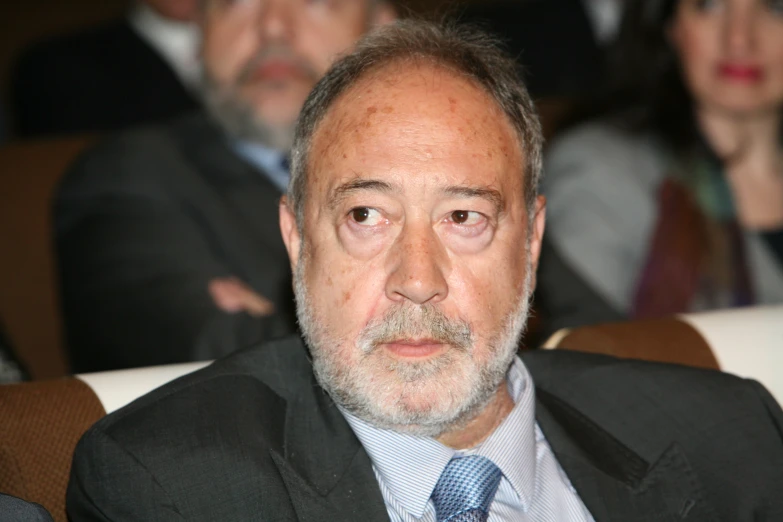 a man with gray hair and a beard wearing a blue tie