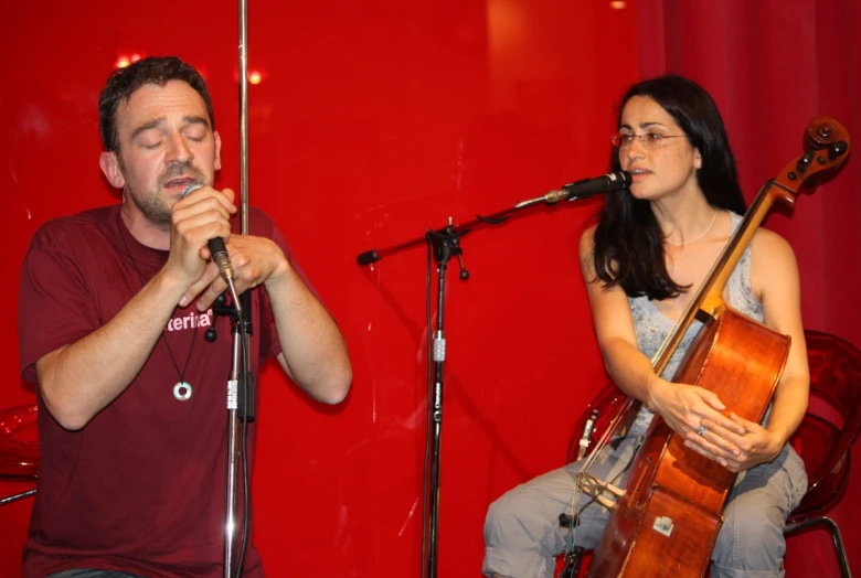 a man playing music on stage with a woman singing behind him