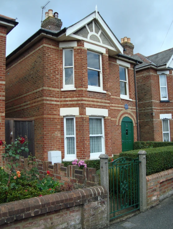 two brick buildings with windows and bushes near by