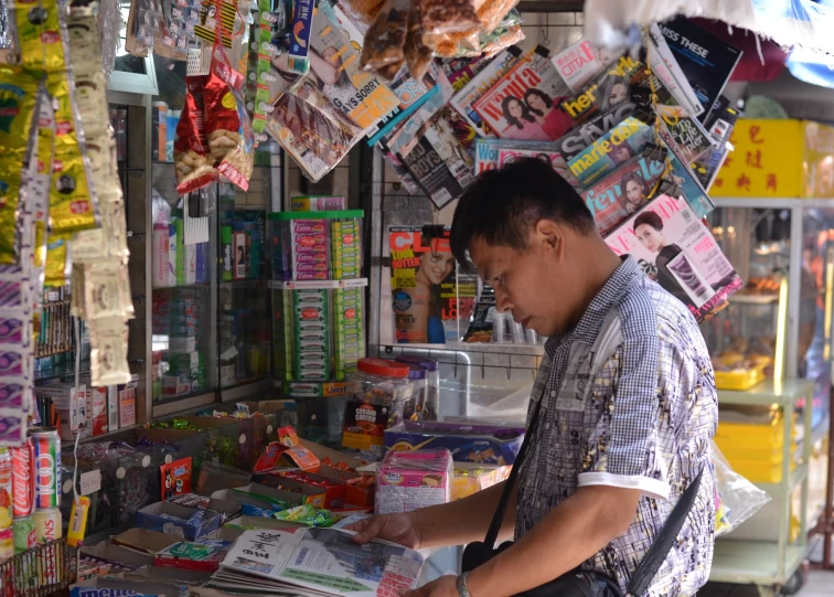 a man standing behind a counter covered in newspapers