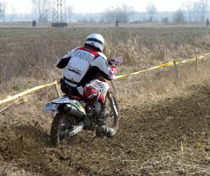 a person rides a dirt bike across a muddy field