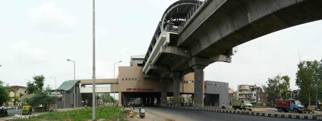 two people on mopeds drive down the street under an overpass