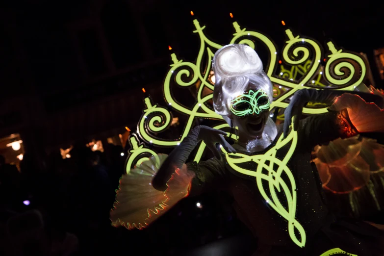 a parade float in the dark with a green mask and decorations