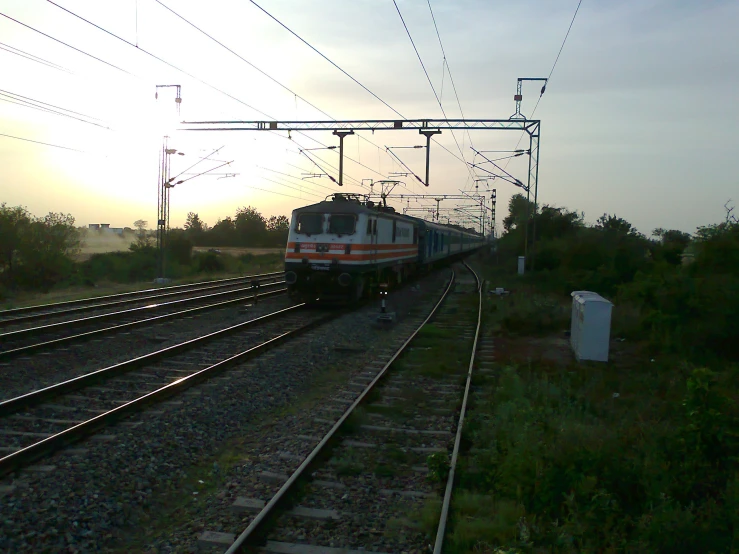 a train riding down a track through a green field