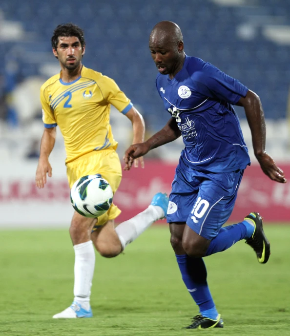 a man kicking a soccer ball around an opponent