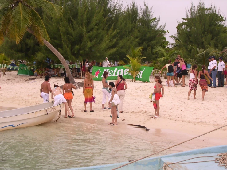 several people are at the beach next to a boat