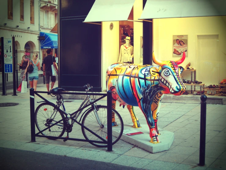 a colorful bull statue sitting next to a bike